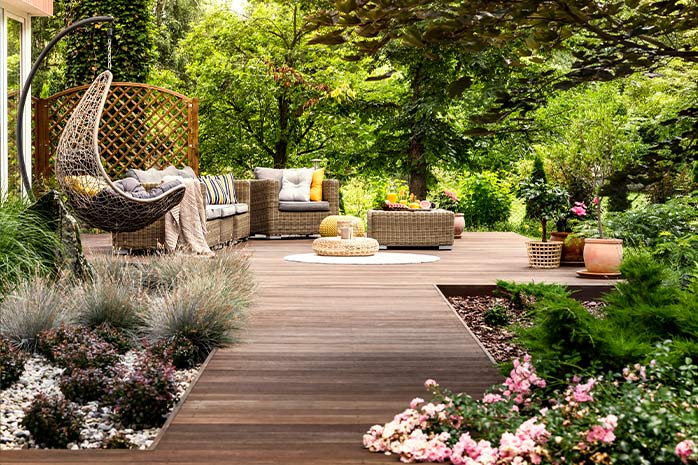 Grande terrasse en WPC avec meubles de jardin au milieu de la verdure, entourée de parterres de fleurs